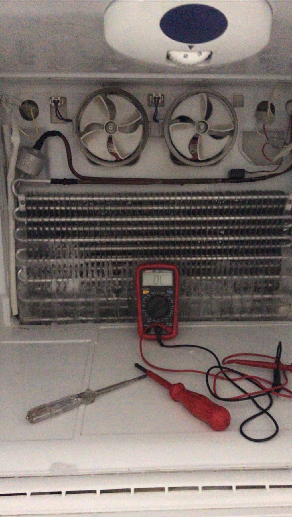 No-frost buzdolabının buzlanmış evaporatörü ve fanları, önünde ölçüm için multimetre