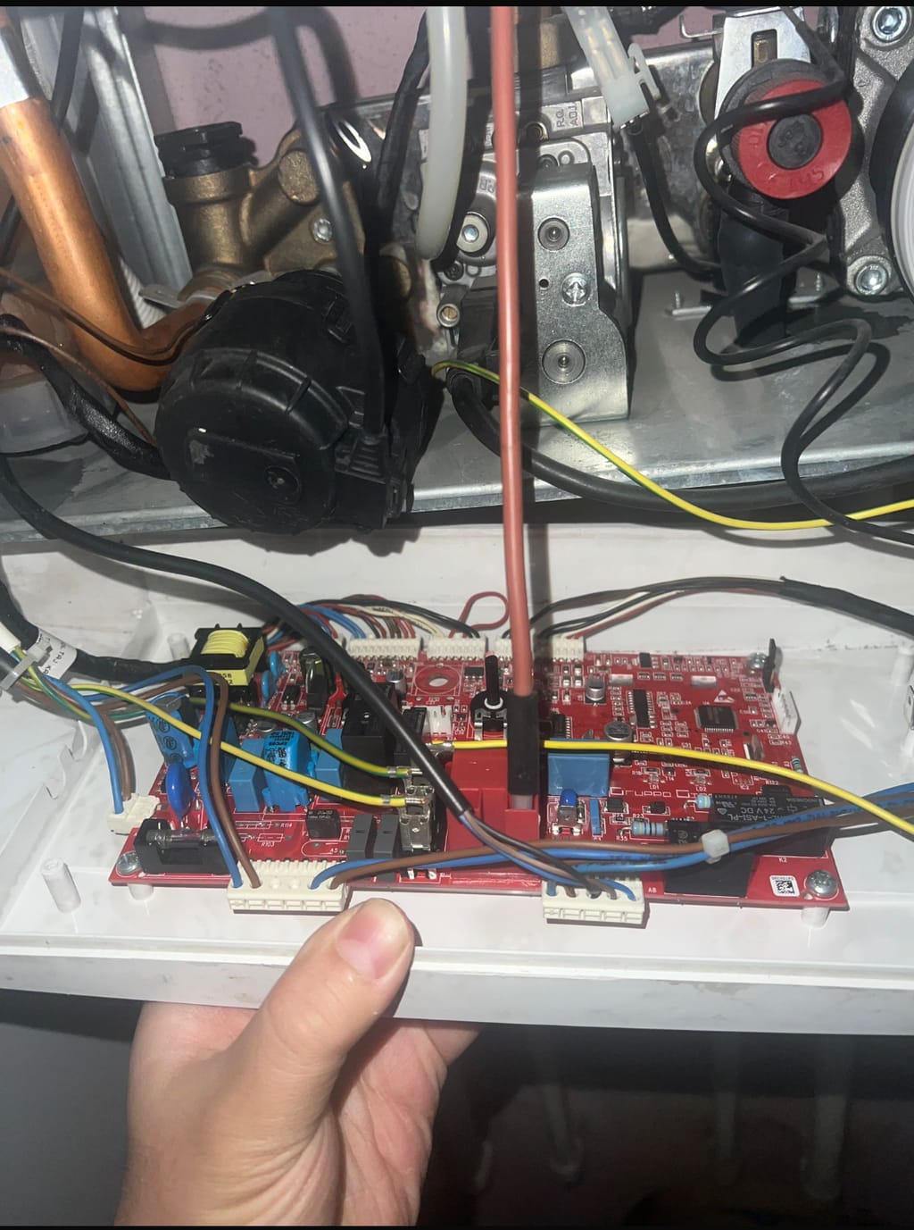 Kapağı açılmış kombinin elektronik kartı, pompası ve gaz valfi